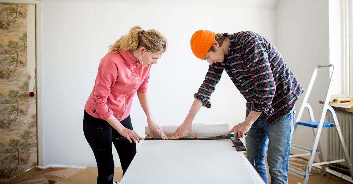 Dame og mann måler tapet mens de pusser opp, til illustrasjon for spare eller låne til oppussing