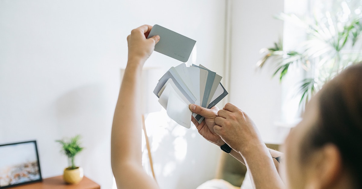 Dame ser på fargerpøver mot vegg, til illustrasjon for tips til oppussing