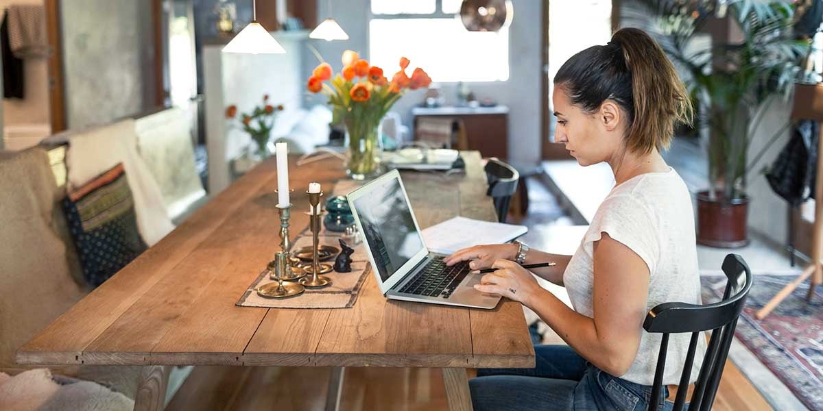 Kvinne sitter på kjøkkenbordet og forbereder seg til å kjøpe bolig