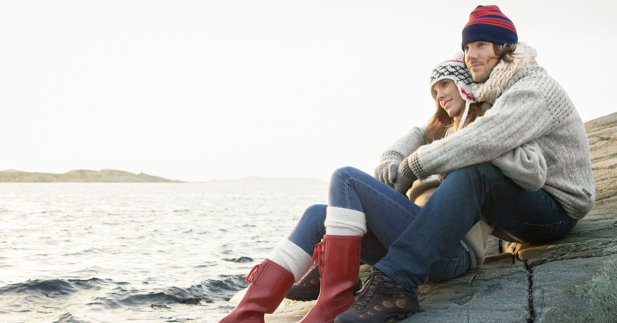 Kvinne lener seg mot mann på svaberg, til illustrasjon for skatt og samboere