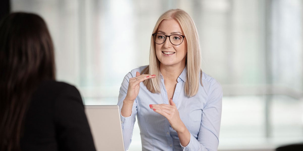 Silje Havdal snakker med kunde og viser med hendene, til illustrasjon for spare eller låne
