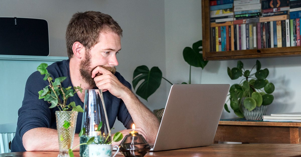 Mann sitter med laptop, til illustrasjon for nettsikkerhet og kortbruk