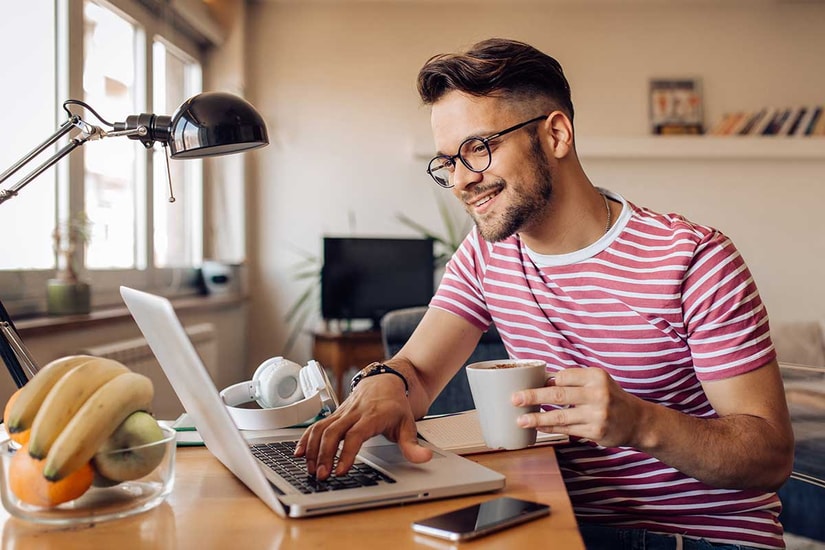 Mann drikker kaffe og ser på pc, til illustrasjon for brukskonto