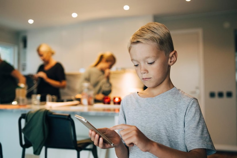 Gutt ser på mobiltelefonen sin, til illustrasjon for mine kort appen til barn