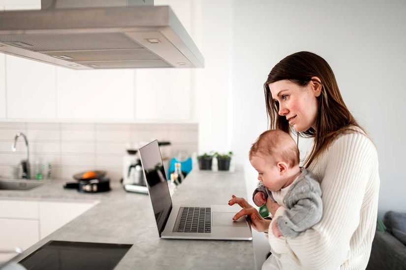 Mor med baby på fanget ved laptop, til illustrasjon for regningskonto