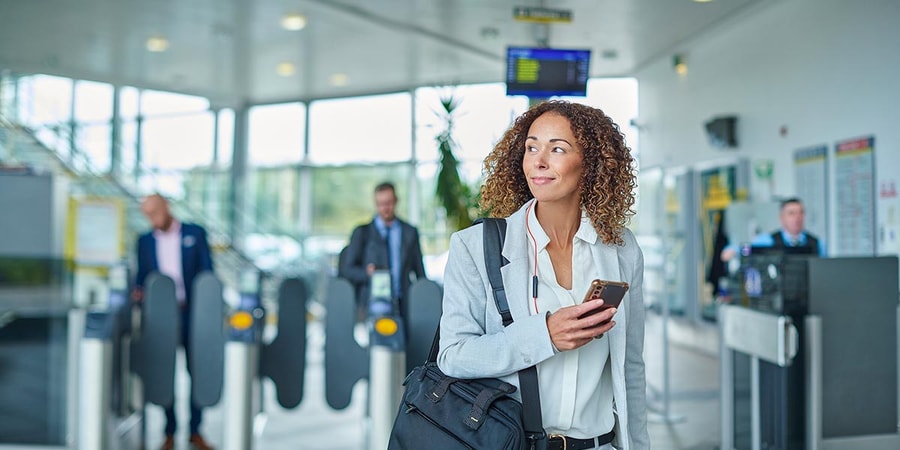 Dame på undergrunnen i London holder en mobil, til illustrasjon for mobilbank for bedrift