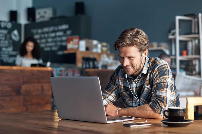 Mann med laptop på cafe