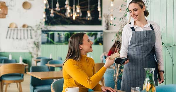 Dame på cafe betaler med telefonen