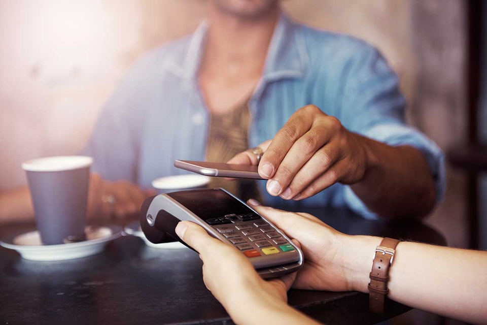Kvinne på kafé betaler med samsung pay på mobilen