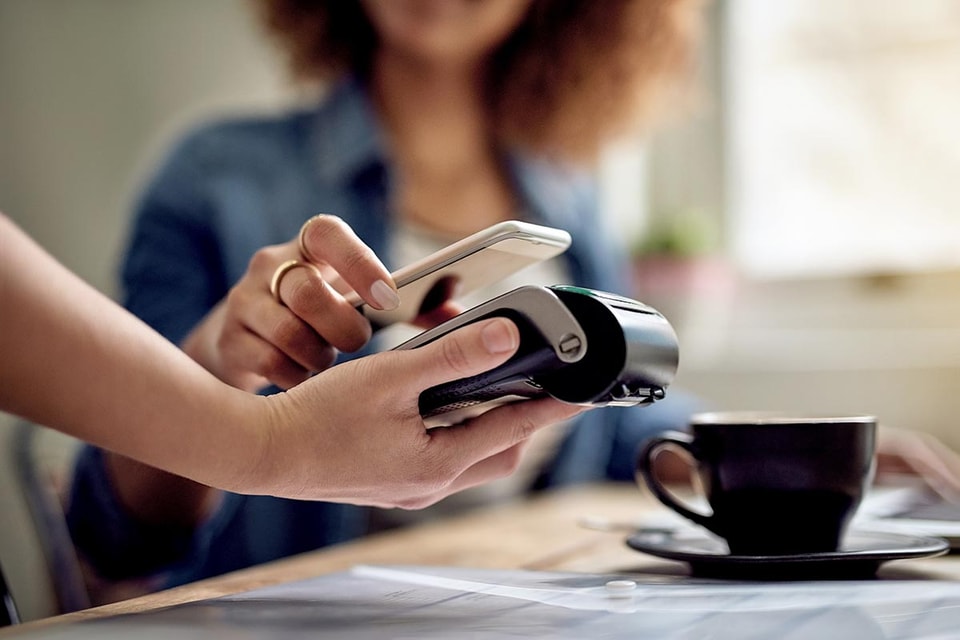 Dame bruker Samsung Pay til å betale for en kopp kaffe