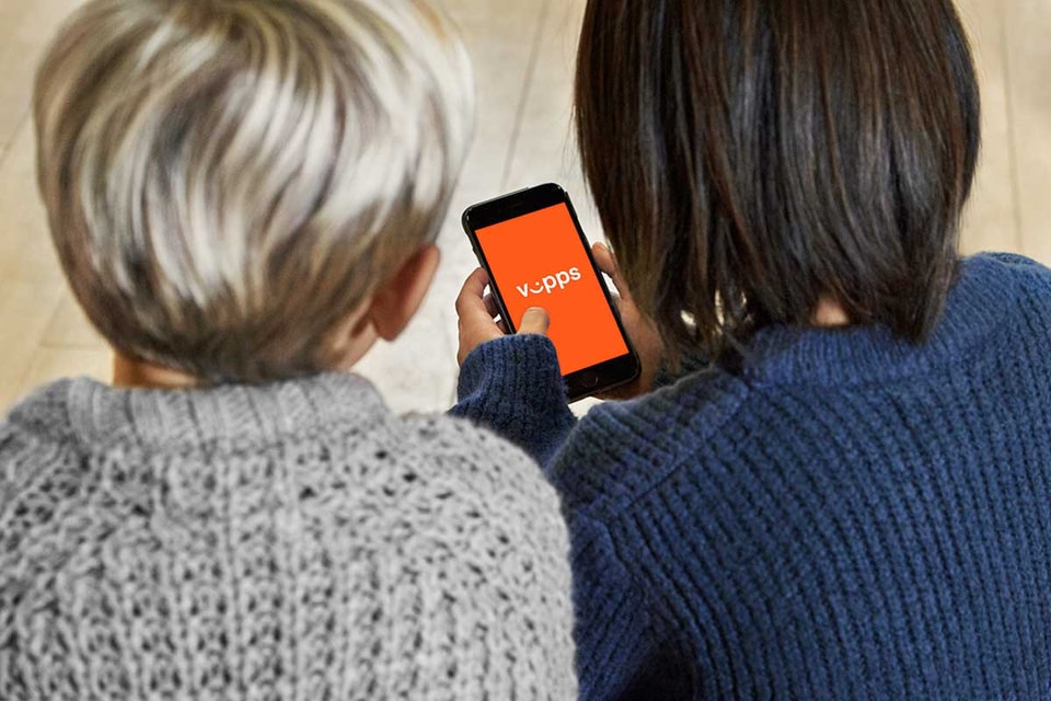 To barn sitter på gulvet og ser på telefonen mens de utforsker Vipps sammen