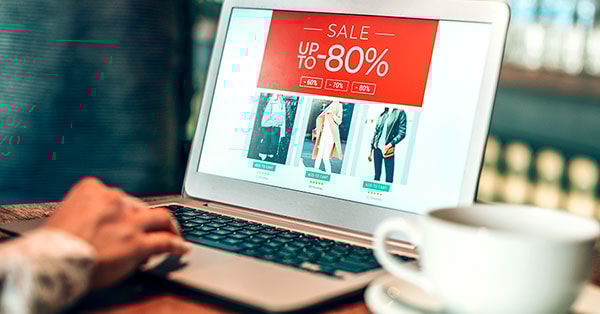 Mann sitter på kafé og ser på salg på datamaskin, til illustrasjon for kredittkort fordeler i BN Bank