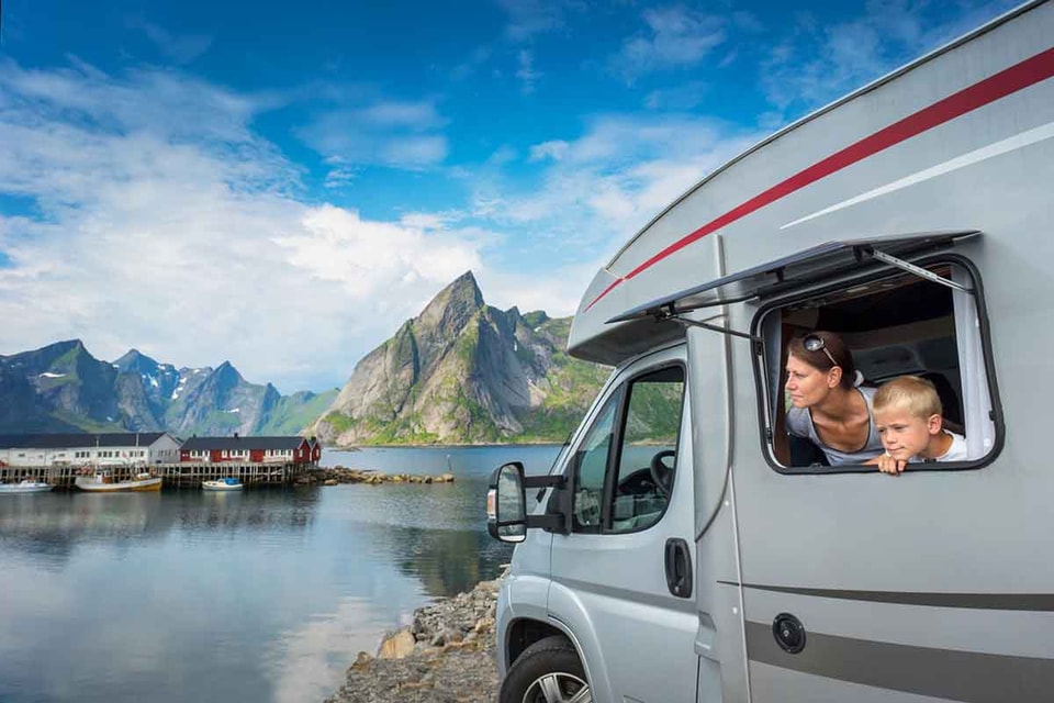 Dame og gutt i en caravan i lofoten med fjell i bakgrunnen, til illustrasjon caravanlån
