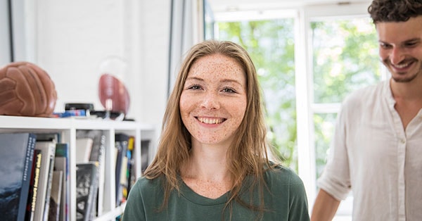 Jente står i leilighet og smiler mens en mann er bak henne, til illustrasjon for medlåntaker