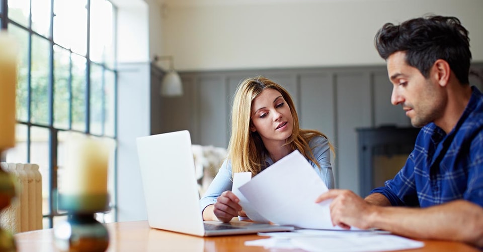 Dame og mann sitter ved et bord og leser dokumenter, til illustrasjon for bytte bolig