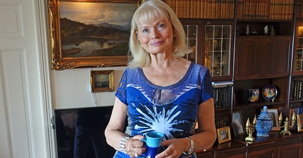 Eva står i stua i sitt eget hjem, til illustrasjon for SeniorLån