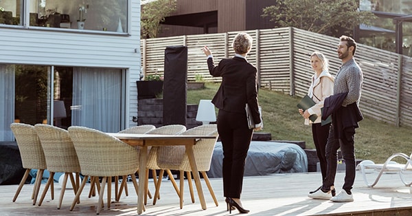 Megler på visning med et par viser fremsiden av en bolig og terrasse