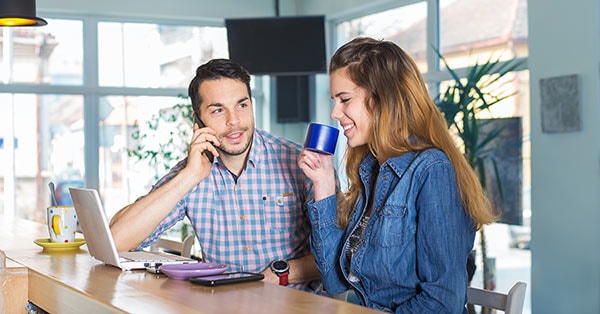 Par sitter i kjøkkenet med pc og mobil, til illustrasjon for å kuppe bolig
