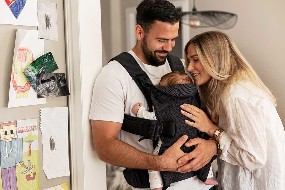 Mor og far med baby i bæresele, til illustrasjon for personlig økonomi