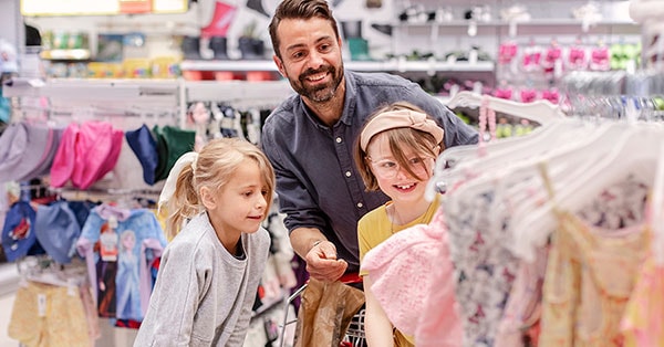 Far er ute å handler klær med to barn, til illustrasjon for 50-30-20