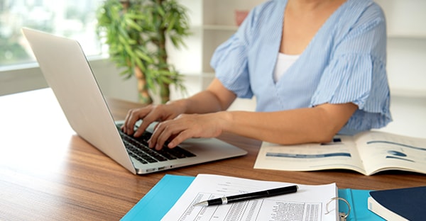 Kvinne jobber på PC på kjøkkenbord, til illustrasjon for bedriftskonto