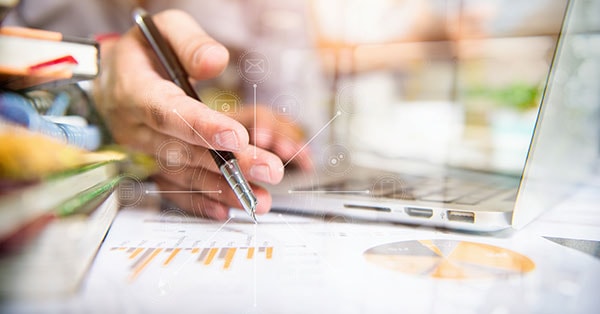 Mann holder penn og macbook, til illustrasjon for regnskapsintegrasjon