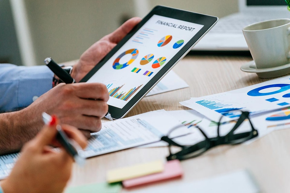 To personer jobber på et nettbrett som viser finansiell informasjon