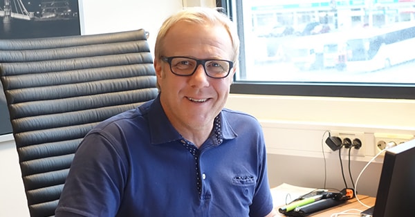 Håvard Christensen sitter på kontoret og smiler