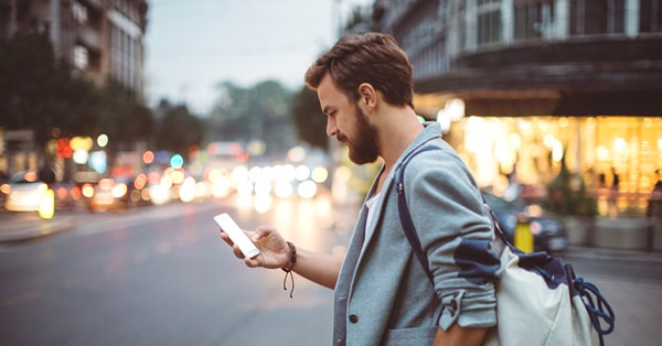 Mann vandrer rundt i sentrum og ser på mobilen, til illustrasjon for finansavtaleloven